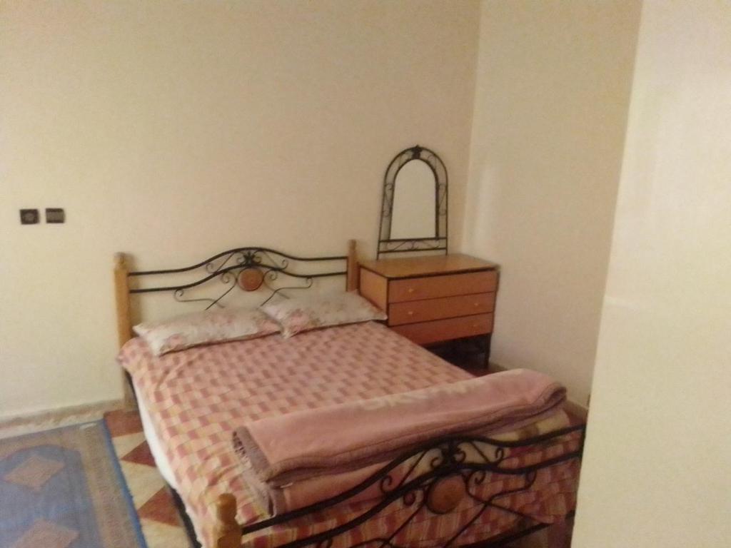 een kleine slaapkamer met een bed en een dressoir bij Apartments in Attaouia Wonderful in Attaouiya ech Chaïbiya