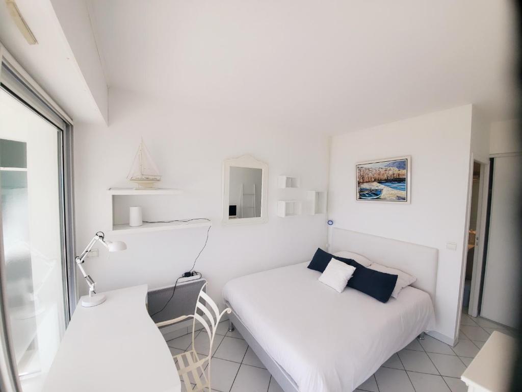 Cette petite chambre blanche dispose d'un lit et d'une fenêtre. dans l'établissement Côté Océan, Vue Mer et Terrasse, à La Rochelle