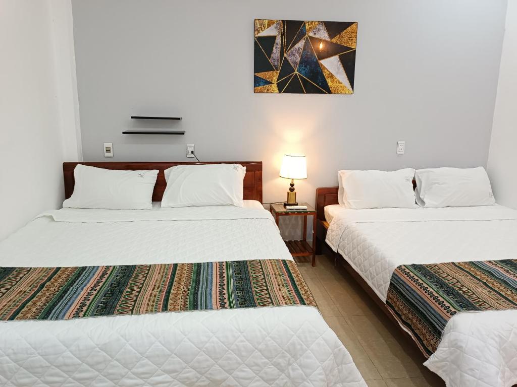 two beds in a room with white walls at An Homestay & Hostel Motorbikes & Tours in Cao Bằng