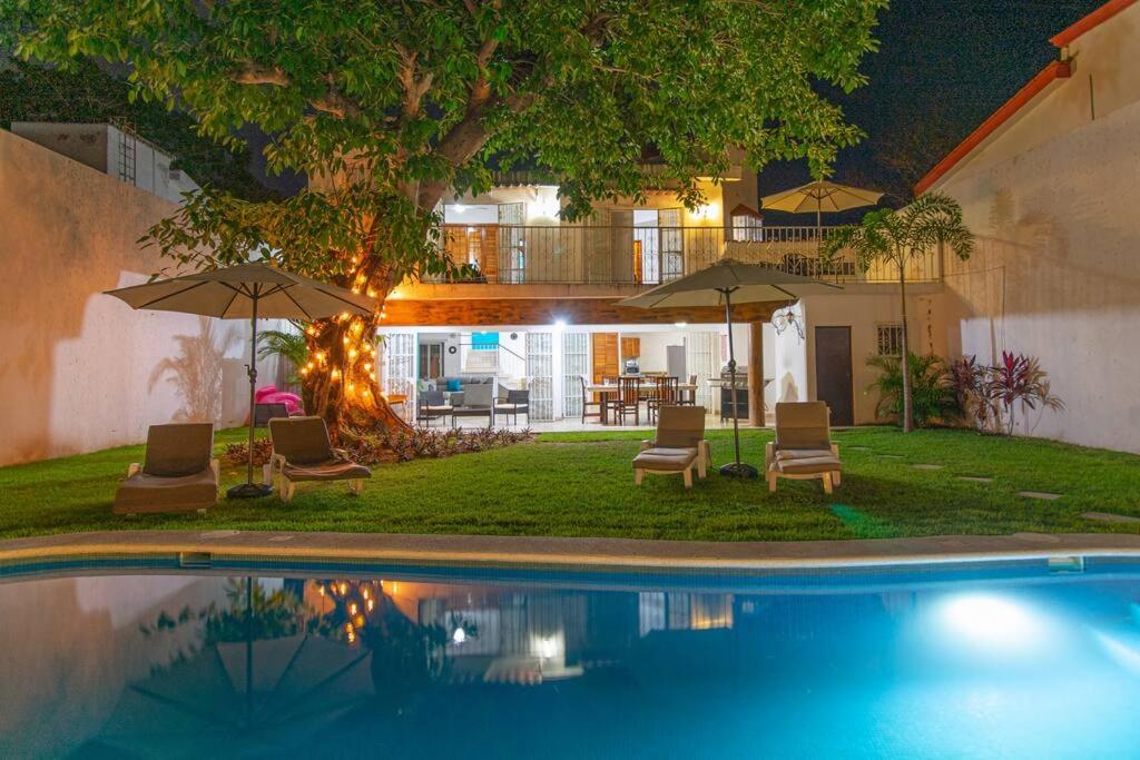 a pool with chairs and umbrellas next to a house at Casa Ines Alberca Privada in Puerto Vallarta