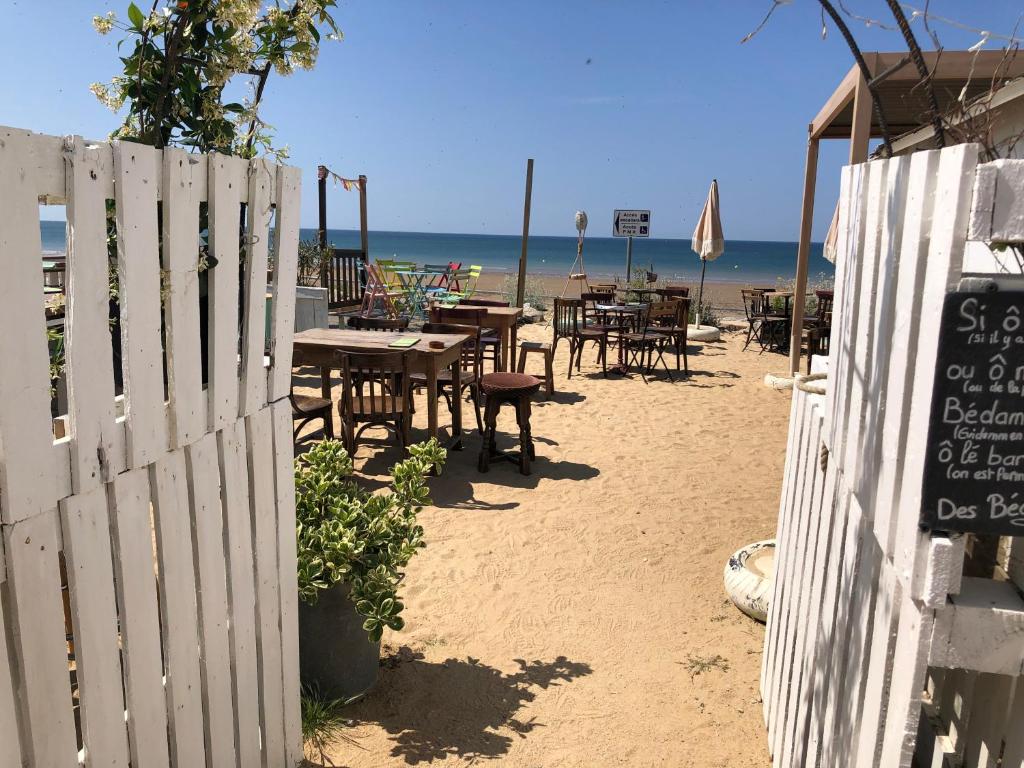 une clôture avec des tables et des chaises sur la plage dans l'établissement Studio vue mer, à Saint-Hilaire-de-Riez