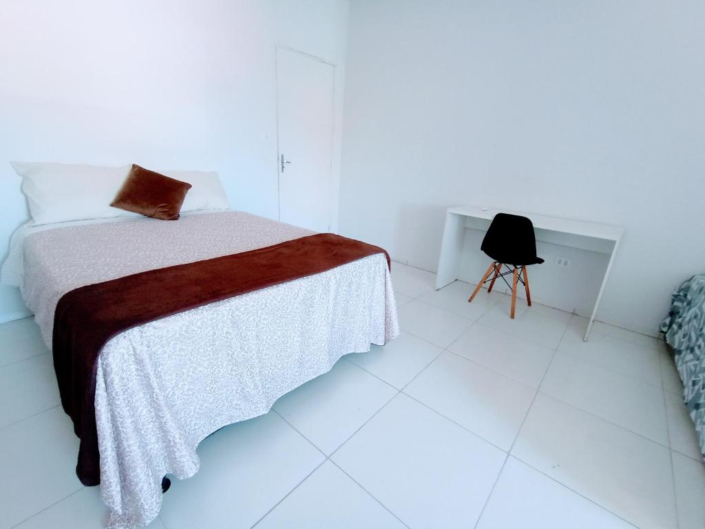 a white bedroom with a bed and a chair at Apartamento Mobiliado no Centro da Cidade in Imperatriz