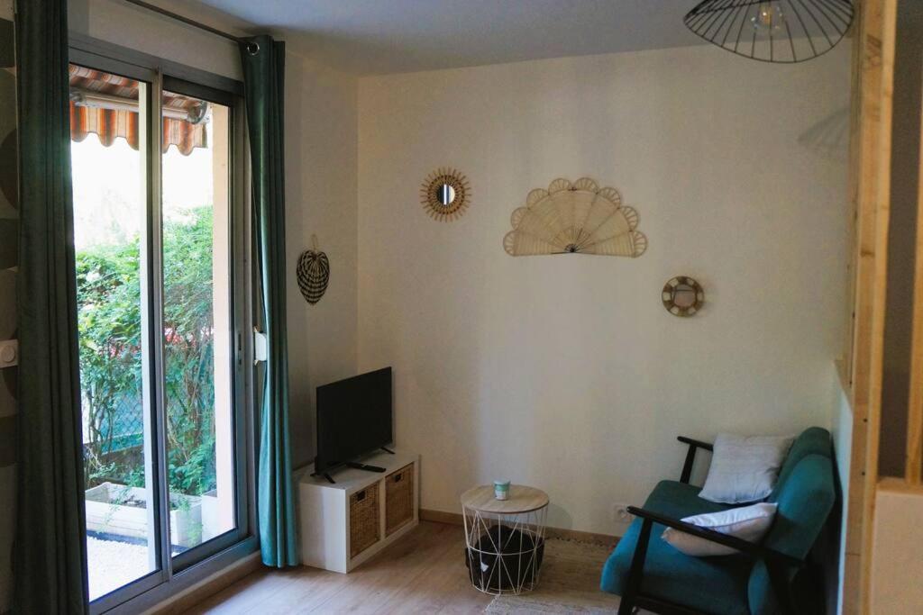ein Wohnzimmer mit einem Stuhl und einem TV in der Unterkunft Studio climatisé et spacieux situé près des Parcs in Vichy