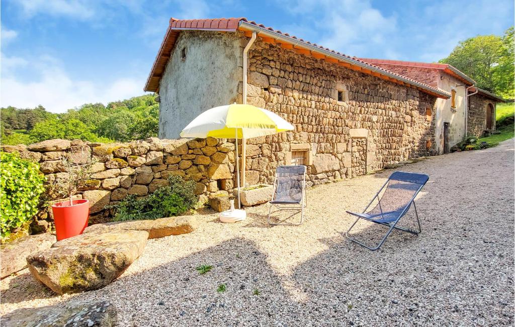 two chairs and an umbrella in front of a stone building at Amazing Home In Essertines-en-chtelne With 3 Bedrooms in Essertines-en-Châtelneuf