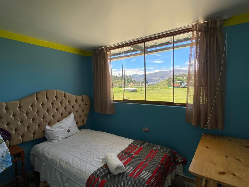 a bedroom with a bed and a large window at Hospedaje Baños del Inca in Cajamarca