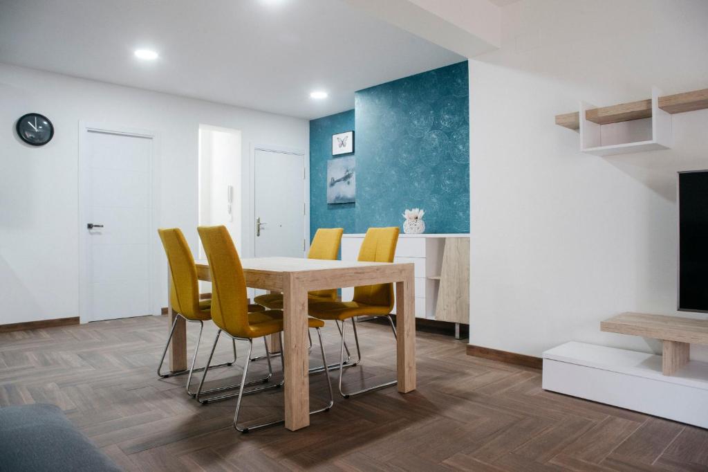 a dining room with a table and yellow chairs at Apartamento La Plana in Castellón de la Plana