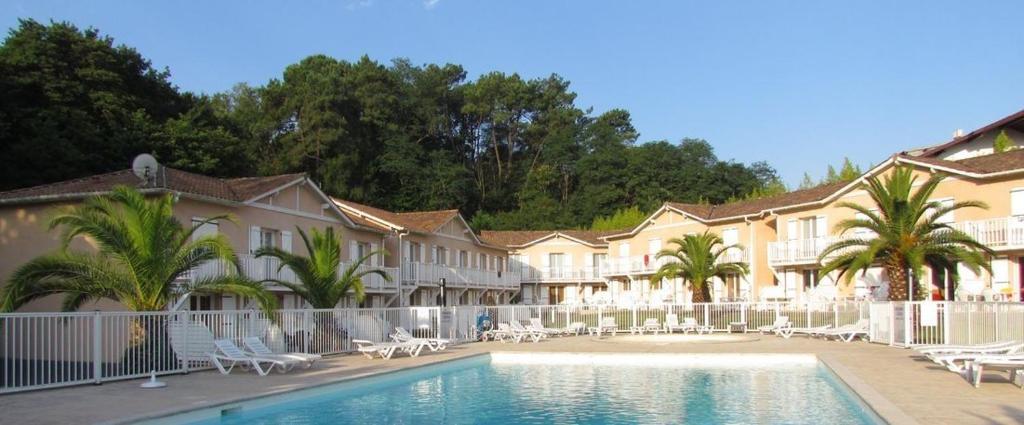 un hôtel avec une piscine en face d'un bâtiment dans l'établissement T3 en duplex avec grande piscine, à Anglet