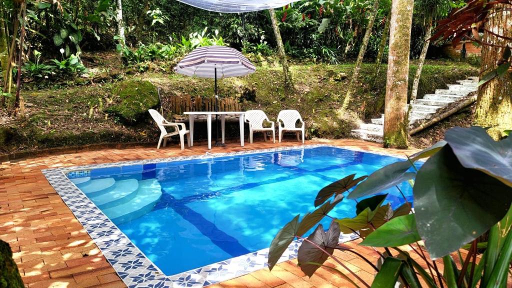 a pool with a table and chairs and an umbrella at Casa Quinta privada con piscinas Billar, Tejo, Jacuzzy climatizado, kiosco in La Vega