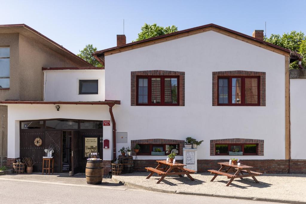 Penzion a vinařství NATURVINI في Miroslav: مبنى أبيض مع طاولتين للتنزه أمامه