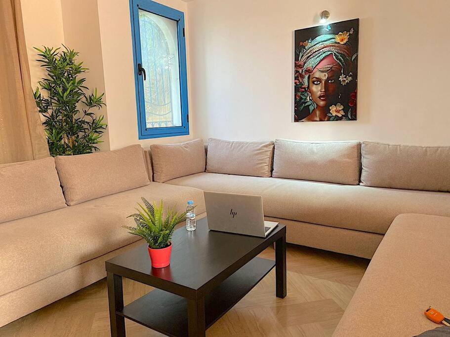 ein Wohnzimmer mit einem Sofa und einem Tisch mit einem Laptop in der Unterkunft Séjour sable et mer: Jardin privé, Plage à 2 pas in Skhirat