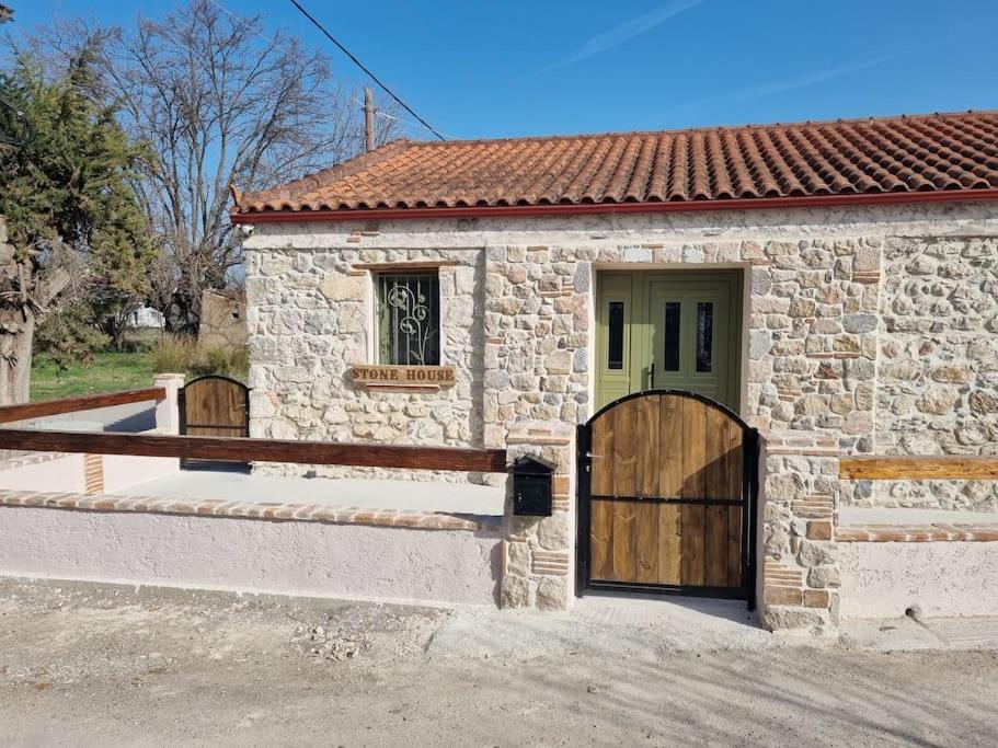 a stone house with a wooden door and a gate at Stone House - Πέτρινο Σαλέ in Alíartos