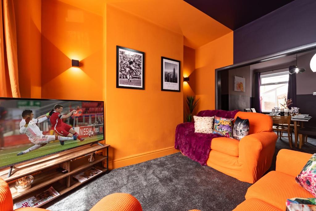 un soggiorno arancione con TV e divano arancione di Ephphatha 4 Beds Central A63 3 Bedrms Free Wifi a Hull
