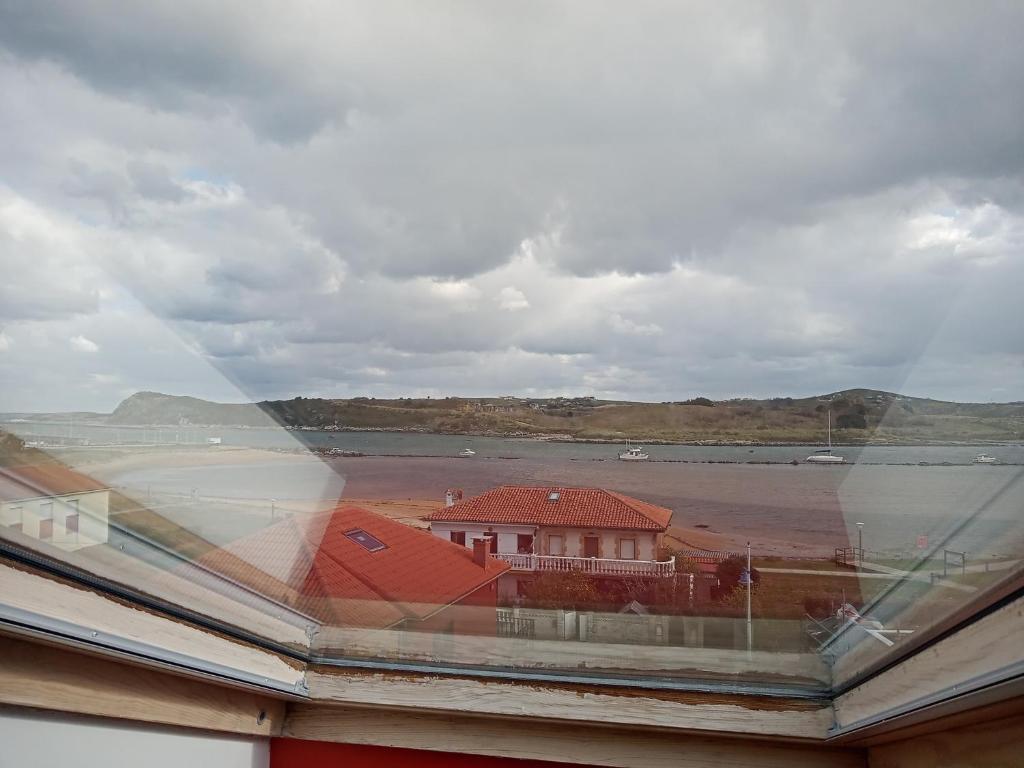 una finestra con vista su una casa e un corpo d'acqua di Apartamento La Riberuca a Suances