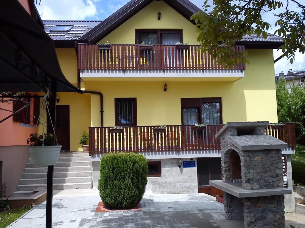 a yellow house with a balcony and a stone oven at Guest House Buk Rastoke in Slunj