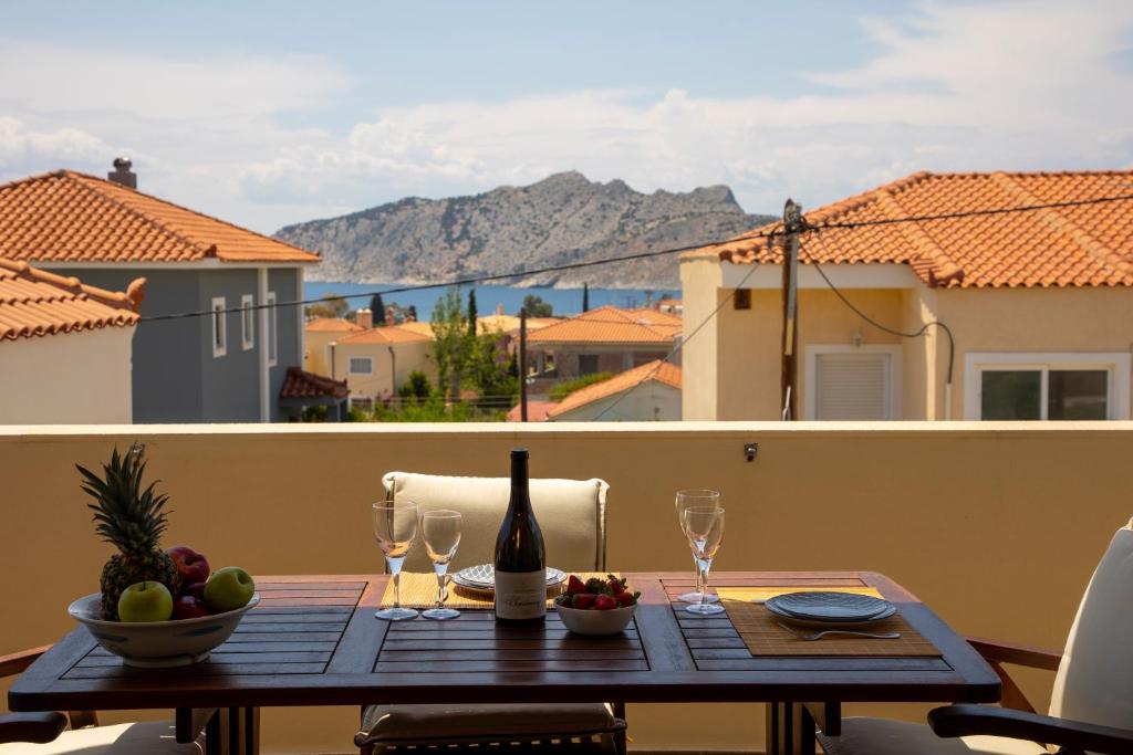 een tafel met een fles wijn en glazen op een balkon bij Nest Aegina Apartments in Perdhika
