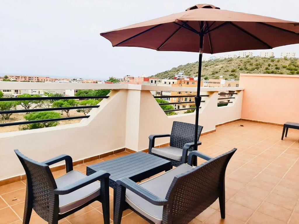 d'une terrasse avec 2 chaises et un parasol sur le balcon. dans l'établissement SUNFLOWER Apartments, à Agadir nʼ Aït Sa
