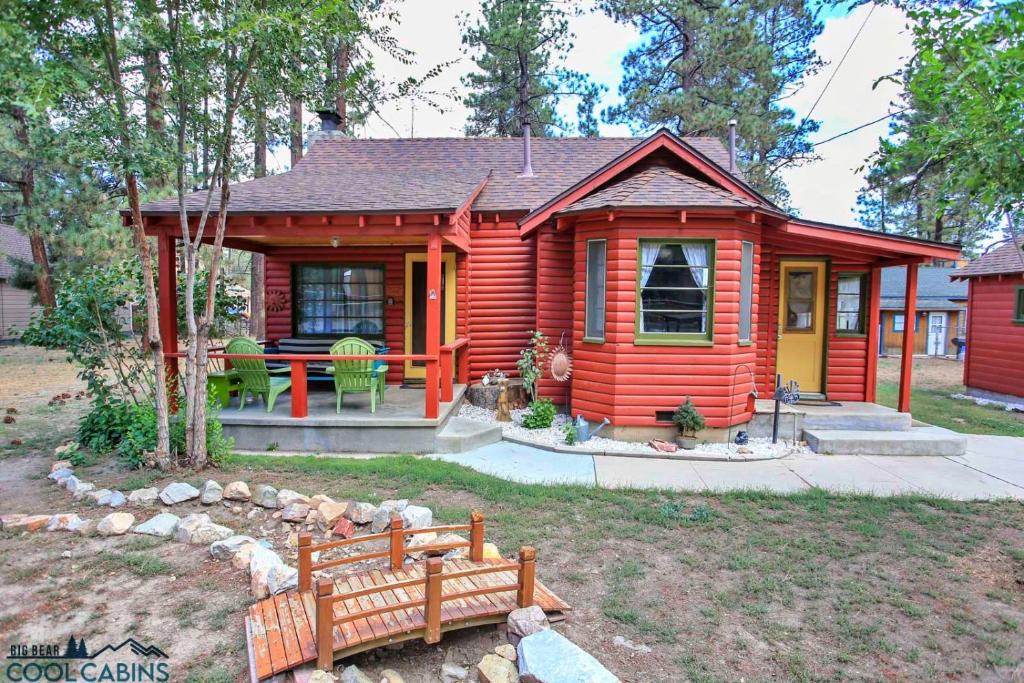 una pequeña casa roja con un banco delante en A Sweet Pine Cabin - Adorable retro home in a peaceful residential neighborhood, en Big Bear City
