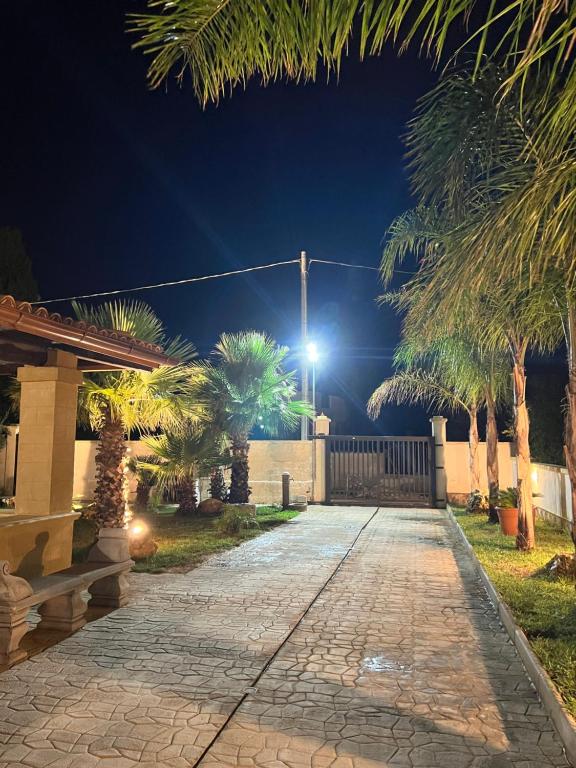 a driveway with palm trees and a street light at Villetta di Venere in Marinella di Selinunte
