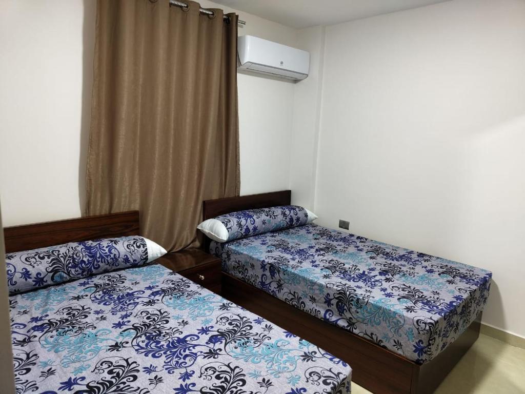 duas camas num quarto com lençóis azuis e brancos em شاليه 120/202 مارينا دلتا em Al Ḩammād