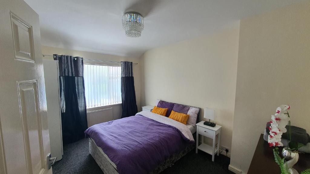 Un dormitorio con una cama con sábanas moradas y una ventana en Spacious 3-bedroom home in Birmingham with driveway parking en Birmingham