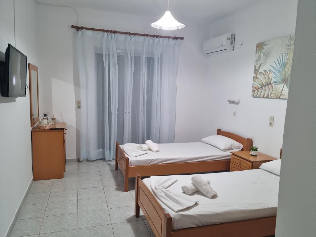 a room with three beds and a tv in it at White rose in Kámpos