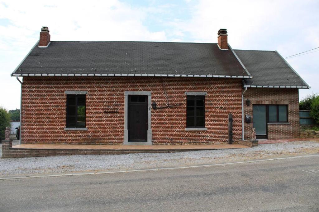 een rood bakstenen gebouw met een zwart dak bij Maison La Thiérache in Momignies