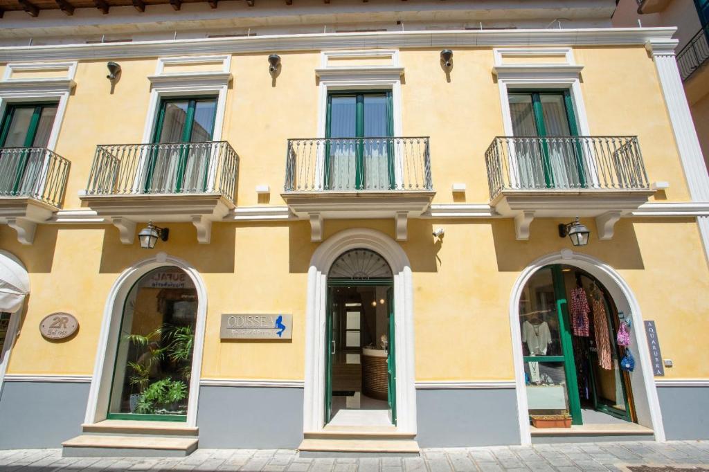 un edificio amarillo con 2 balcones en Odissea Residence e Rooms, en Santa Maria di Castellabate