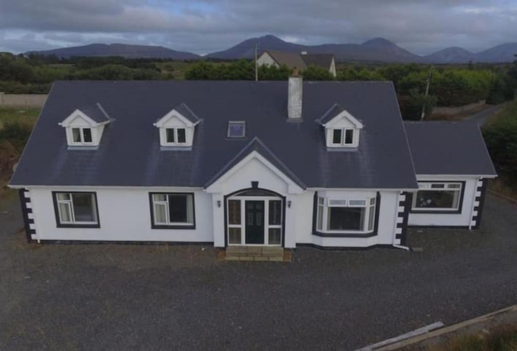 ein weißes Haus mit blauem Dach in der Unterkunft Baile Go Deo. in Falcarragh