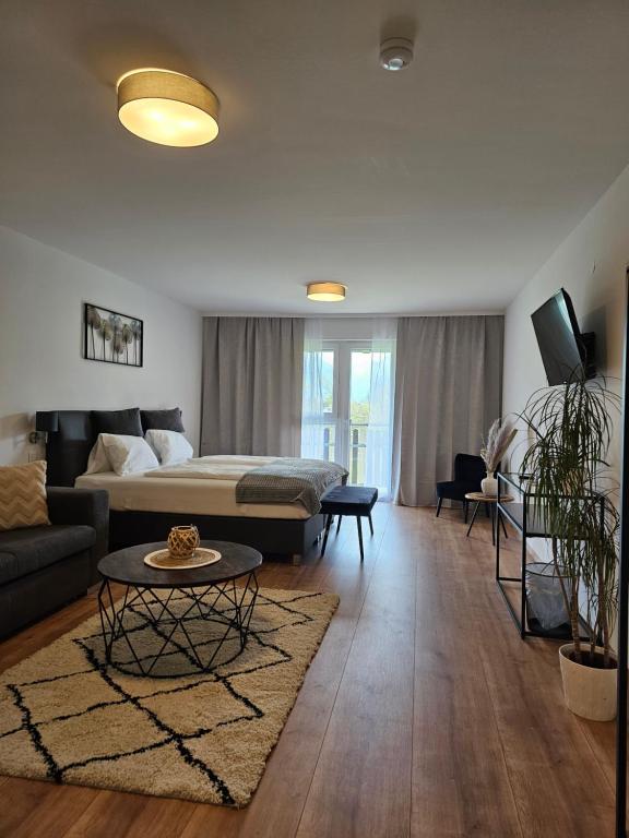 a living room with a bed and a couch and a table at Hotel Fuchs & Hase SELF CHECK IN in Rosegg