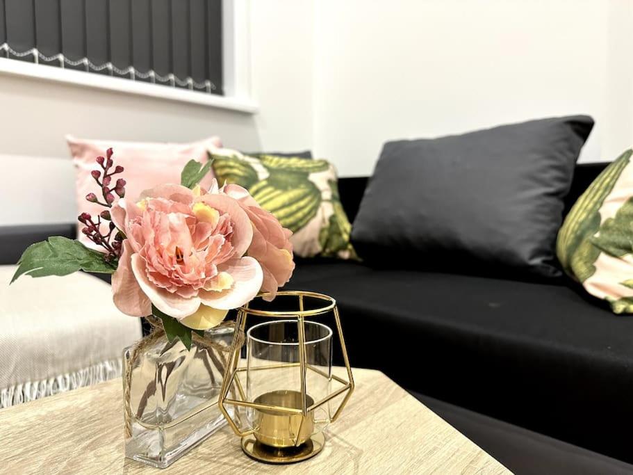 een vaas met bloemen op een tafel met een bank bij Spacious and Elegant Apartment in Birmingham