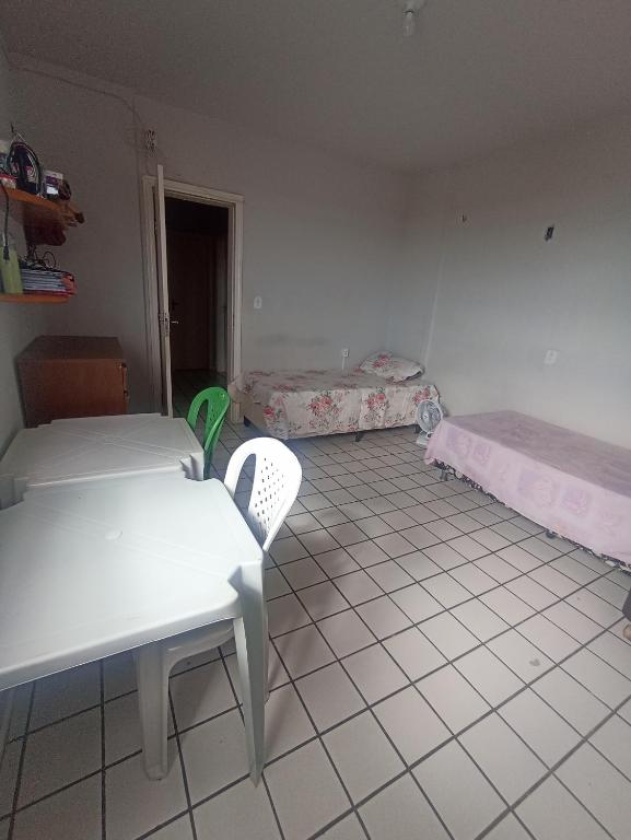 Habitación con 2 camas, mesa y sillas en Cantinho para mulheres, en Parnaíba