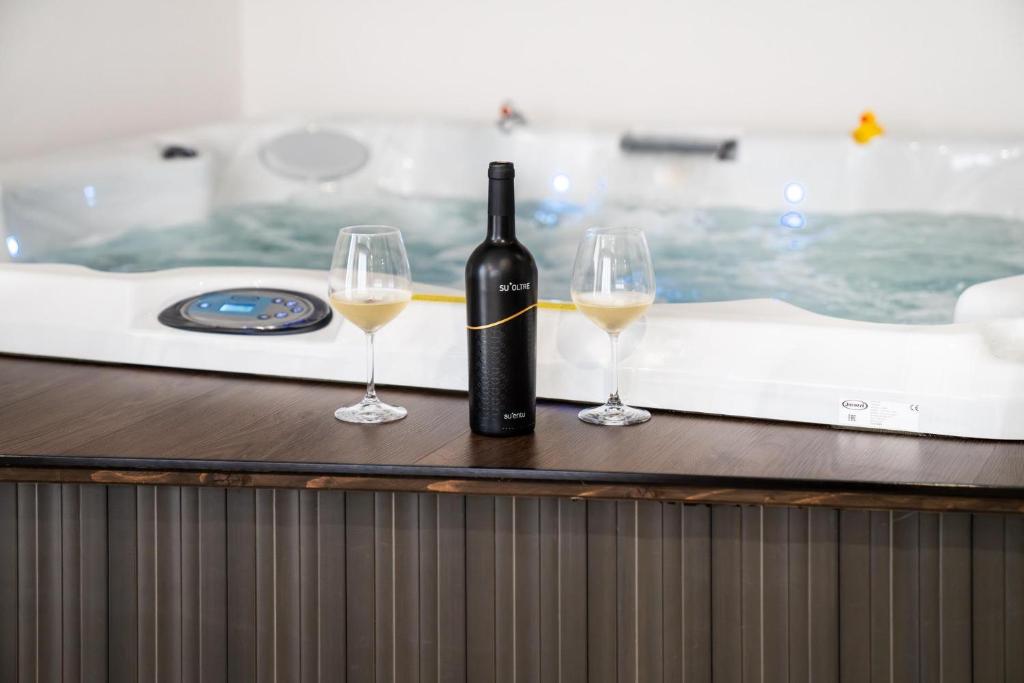 a bottle of wine and two glasses on a bath tub at L'OLEANDRO Room's - Suite & Spa da Giuseppe in Gonnosfanàdiga