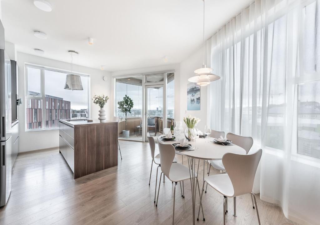 comedor y cocina con mesa blanca y sillas en Sif Apartments by Heimaleiga, en Reikiavik