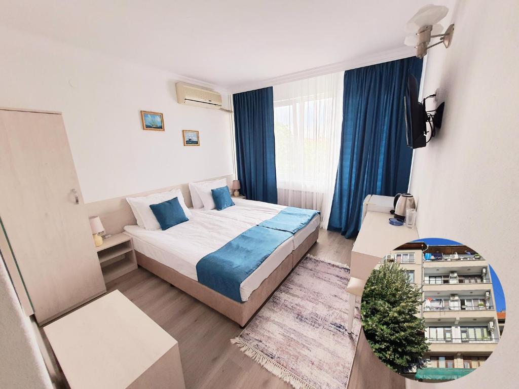 Habitación de hotel con cama y cortinas azules en Guest House Kolev, en Nesebar