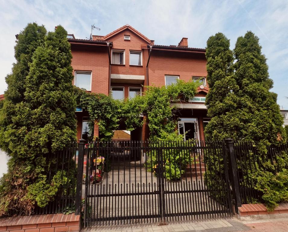 a black fence in front of a house with trees at VillaAnita in Augustów