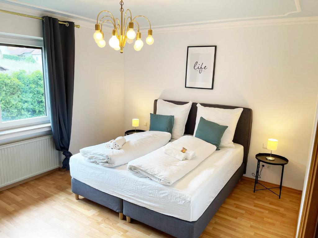 a bedroom with a bed with two pillows and a chandelier at Bavaria Home: Terrasse, Küche, Netflix in Wolnzach
