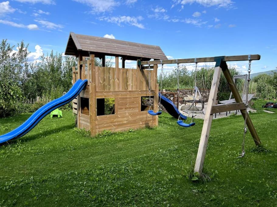 un parque infantil de madera con tobogán y estructura de juegos en Haus am Hügel, 