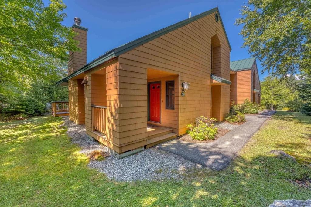 una pequeña casa con una puerta roja en un patio en New Property! Updated 3 bed 3 bath condo with mountain ski slope views in Bretton Woods, en Bretton Woods
