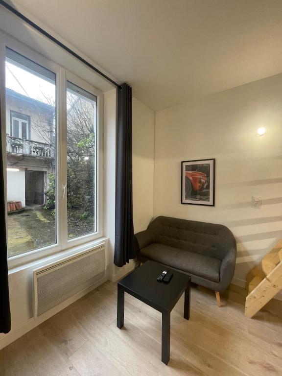 een woonkamer met een bank en een groot raam bij Le petit Louis Fort - Studio cosy-Gratte Ciel in Villeurbanne