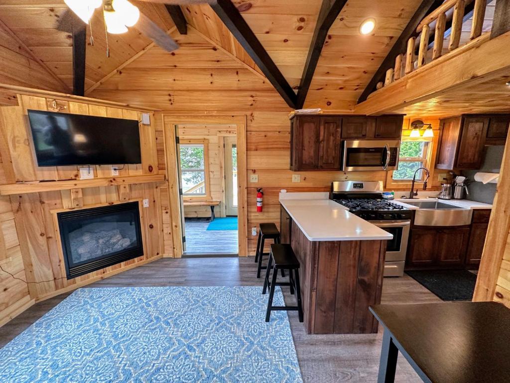 a kitchen with a fireplace in a log cabin at BMV7 Tiny Home village near Bretton Woods in Twin Mountain