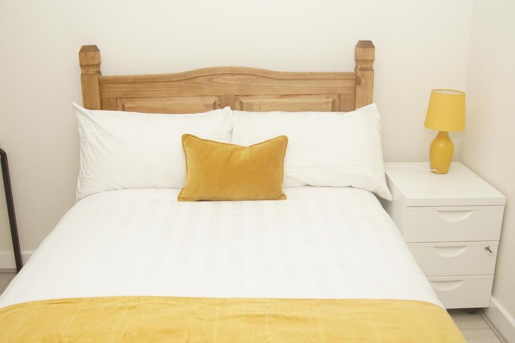 a white bed with a wooden headboard and white pillows at Deluxe City Centre 4 Bedroom Entire Town House in Leeds