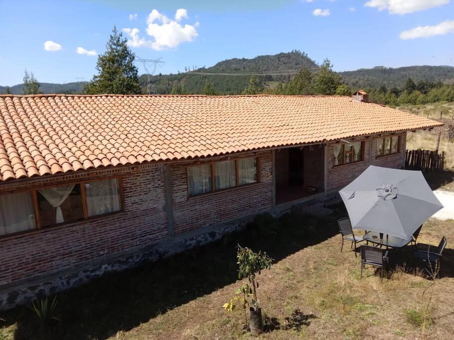 een huis met twee stoelen en een paraplu ervoor bij Hermosa cabaña en zacatlan puebla la escondida in Jicolapa