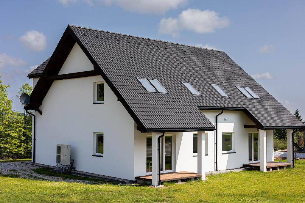 a white house with a black roof at Apartamenty pod Jagodną in Spalona