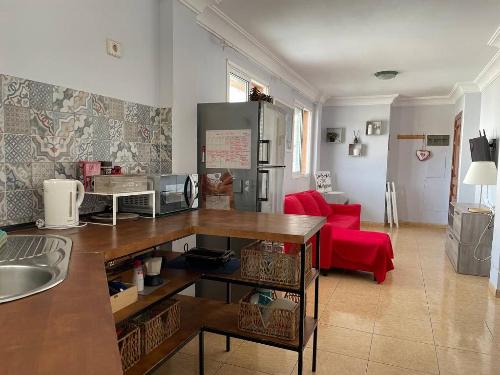 eine Küche und ein Wohnzimmer mit einem roten Sofa in der Unterkunft Amber House in Arinaga
