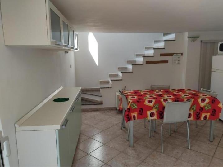 uma cozinha com uma mesa com cadeiras e uma escada em Casa vacanze Alloro em Mangia