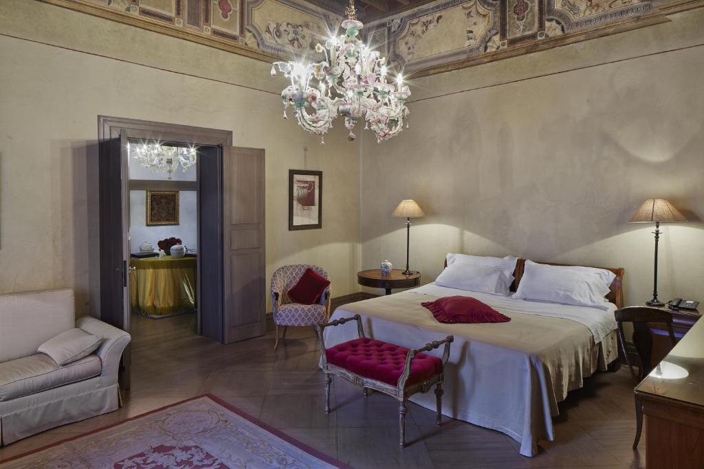 a bedroom with a large bed and a chandelier at Albergo Cappello in Ravenna