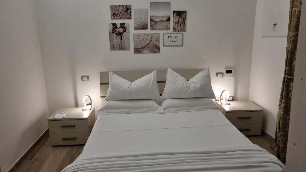 una camera da letto con un grande letto bianco con due comodini di Il civico storico a Brindisi