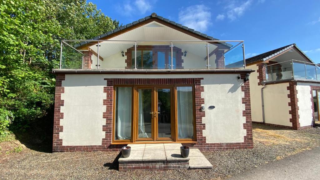a brick house with a large glass window on it at Pine Lodge - Two Bedrooms, High Bickington close to Umberleigh , Barnstaple , Bideford in High Bickington
