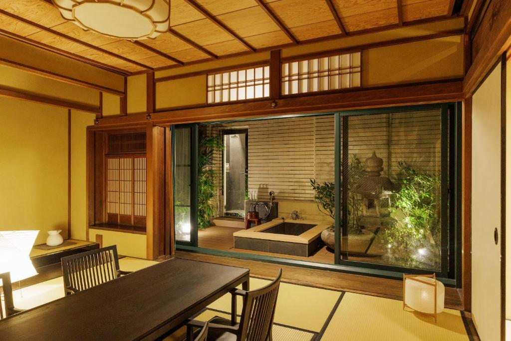 een eetkamer met een tafel en een groot raam bij Marufukuro in Kyoto