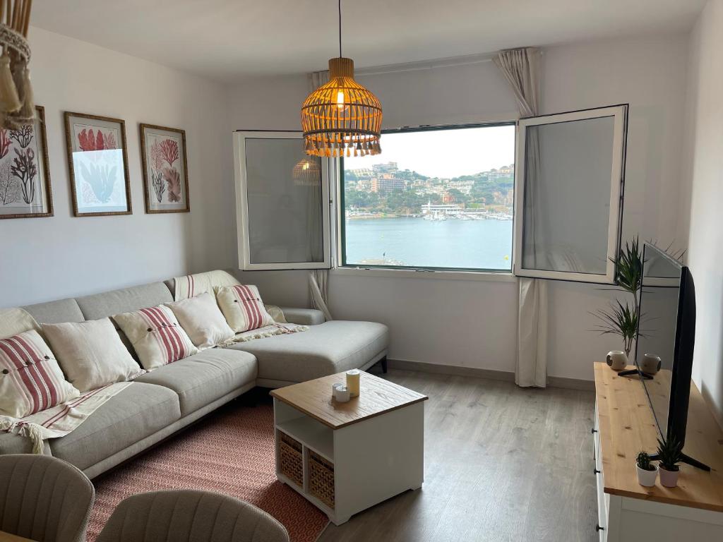 un soggiorno con divano e una grande finestra di Arena, exquisito apartamento con aire acondicionado en la playa a Sant Feliu de Guíxols